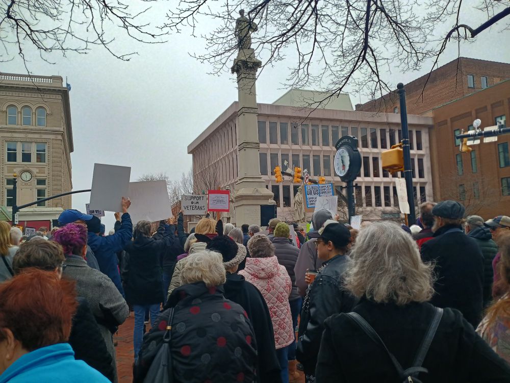 Crowd of people in downtown Lancaster, holding signs. 