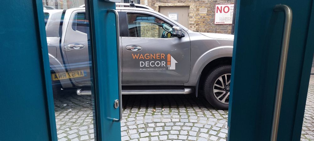 Doors open to reveal a view of a vehicle with the logo of a company called 'Wagner Decor' 