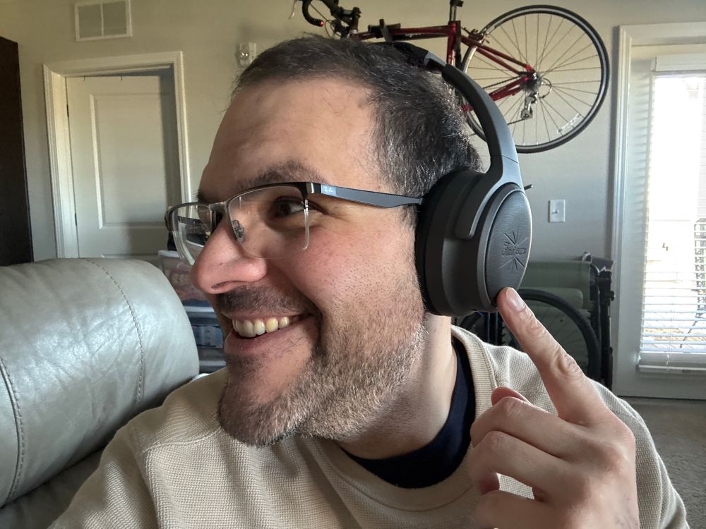 Anna wearing headphones and pointing at them. 