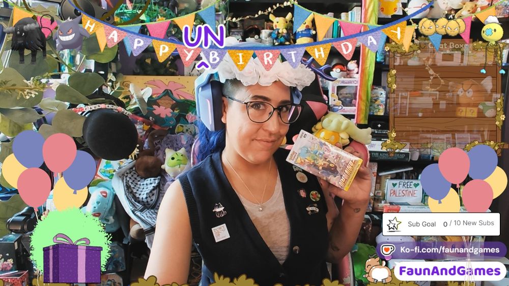 Nonbinary streamer FaunAndGames, a tan skin femme perceived person with brown, blue, and purple hair, is wearing gaming headphones with antlers on them and a flower crown. They are smiling and holding up a box of Pokemon cards at the camera. Around them are Twitch stream decorations and a tone of nerdy video game memorabilia. 