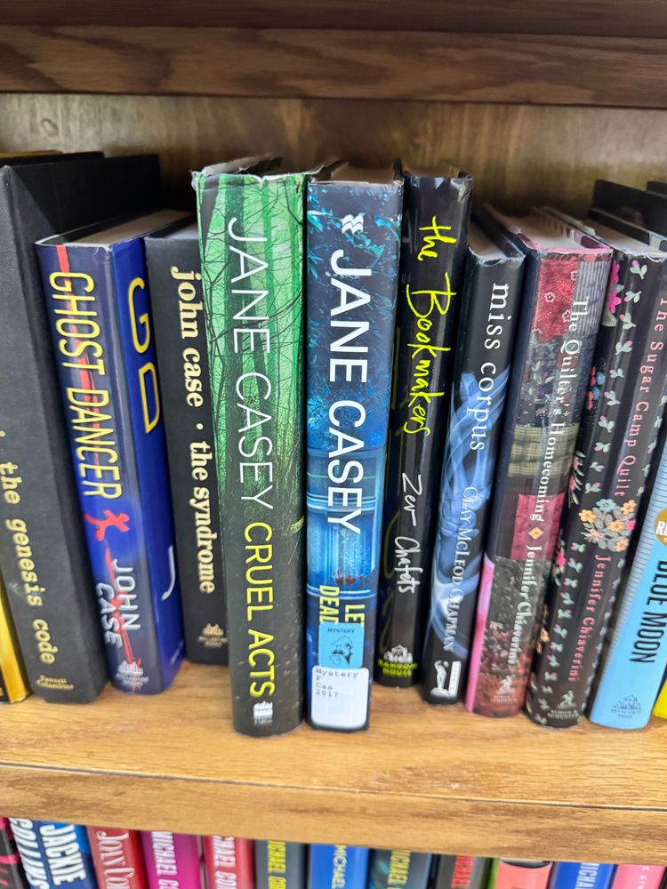 A shelf featuring library books for sale, 2 of which are from Jane Casey’s Maeve Kerrigan series. 
