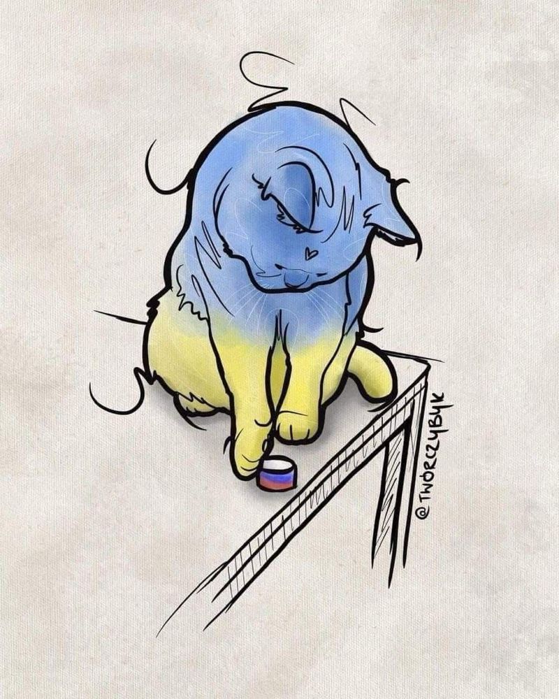 Gelb-blaue Katze stößt Klötzchen in russischen Farben vom Tisch. 
