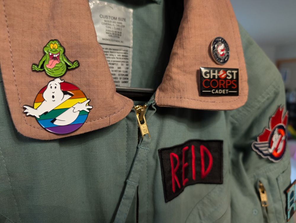 A Ghostbusters flightsuit with a Pride pin and other pins on the collar.