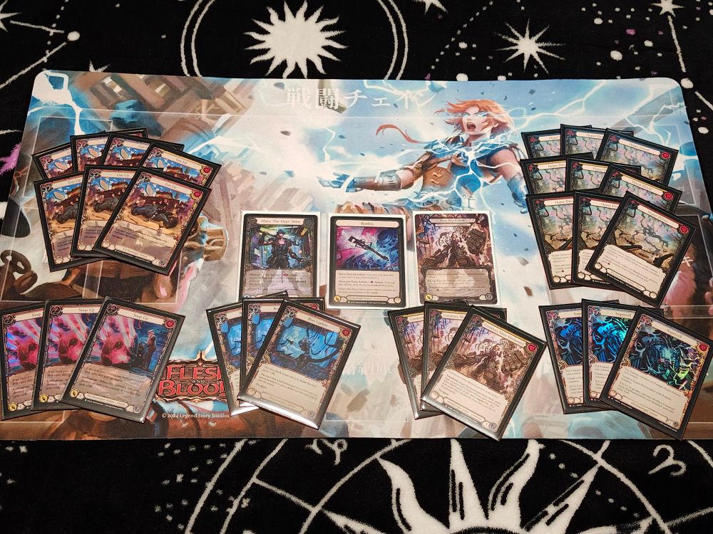 Displayed are the following cards all lying on top of a High Octane playmat:
Cold Foil Maxx "The Hype" Nitro
Cold Foil Banksy
Cold Foil Marvel Construct Nitro Mechanoid
3x Cold Foil Construct Nitro Mechanoid
3x Cold Foil Hyper Driver Red
3x Cold Foil Hyper Driver Yellow
3x Cold Foil Hyper Drive Blue
3x Rainbow Foil Supercell
3x Rainbow Foil Bios Update
3x Extended Art Rainbow Foil Soup Up Red
3x Extended Art Rainbow Foil Gas Up Red
1x Extended Art Rainbow Foil Gas Up Yellow
3x Extended Art Rainbow Foil Gas Up Blue