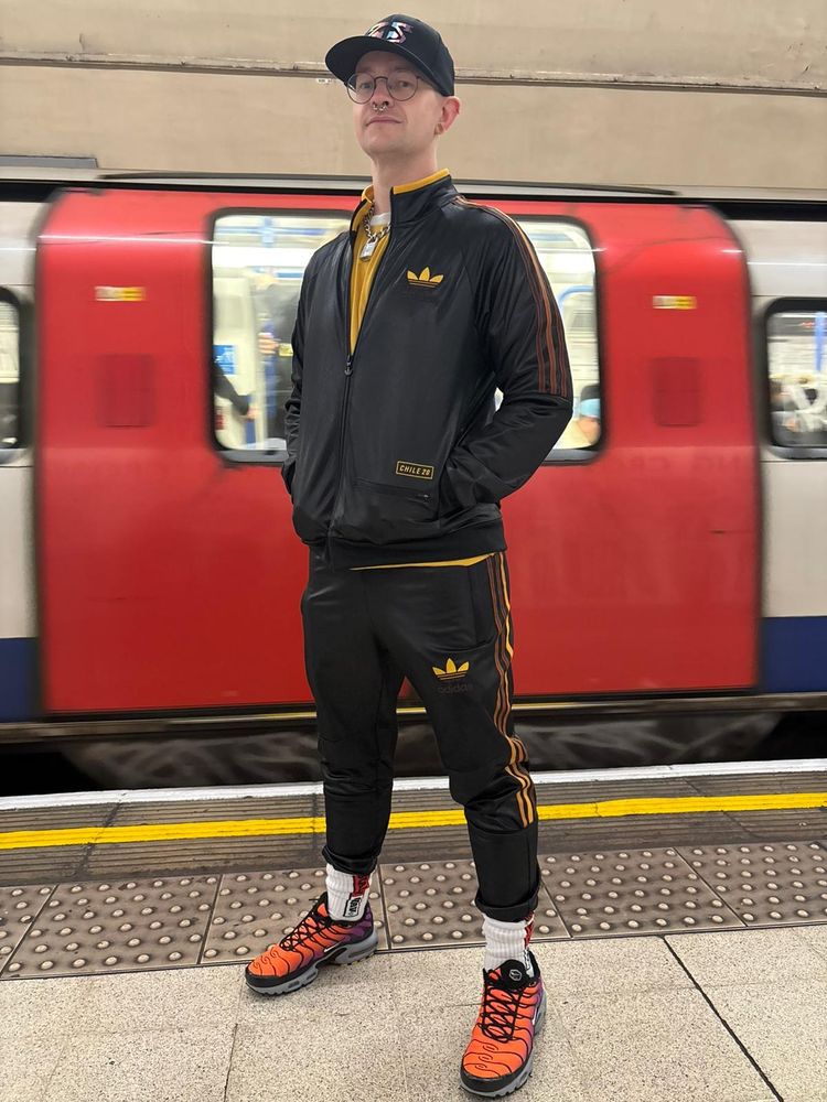 Me in front of a moving underground train in Adidas Chile (brown and orange) with orange TNs on. Hands in pockets. Nasty pig cap