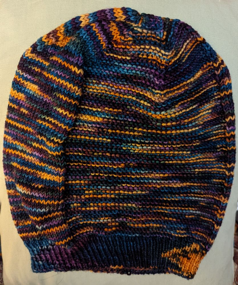 A knitted hat in variegated yarn of blues, purples and oranges. 
