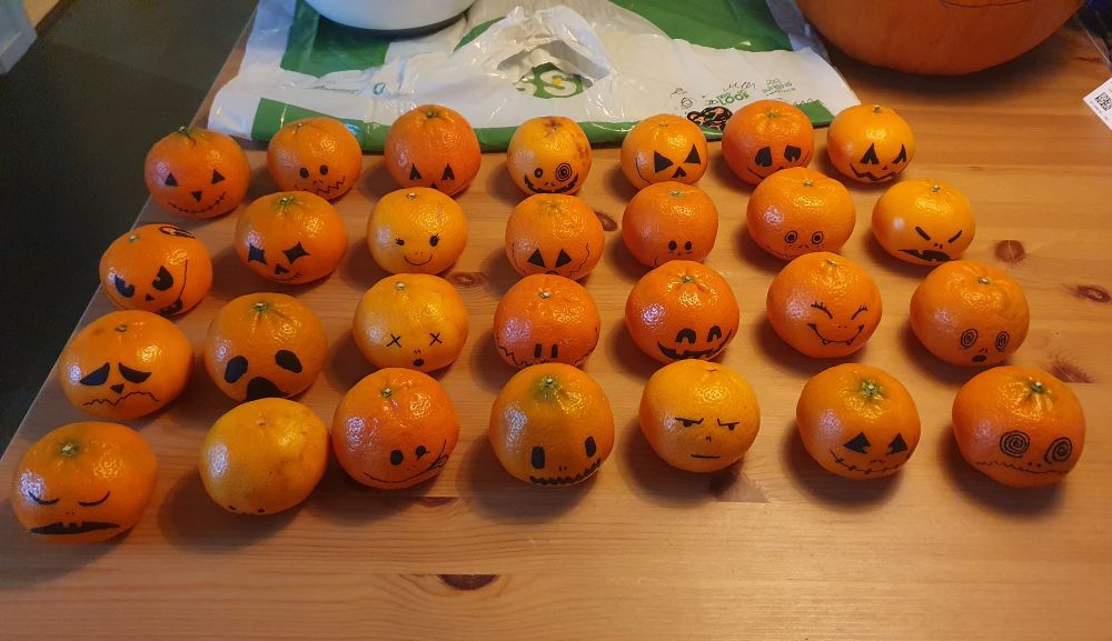 En haug med klementiner stilt opp på geledd. Alle har påtegnet rare fjes.