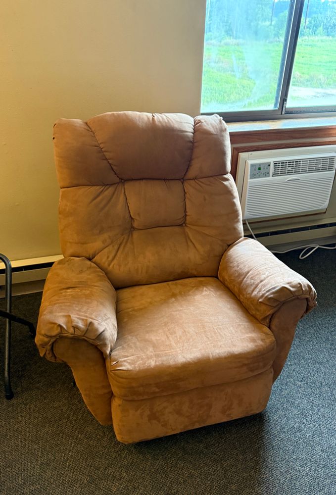 Well cushioned brown suede armchair in a hotel room