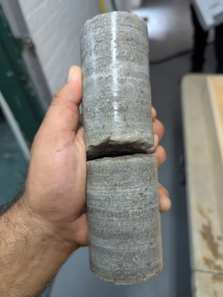 Side view of three and four inch pieces of rock core that is gray with specs of mica. All the gray is almost pure quartz