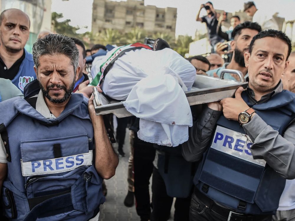 A group of journalists from Al Jazeera carry the shrouded body of their dead colleague on a stretcher.