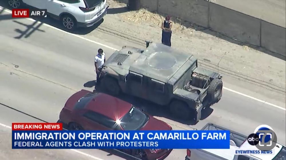 The protestor stands bolt upright in front of the Humvee that has to stop