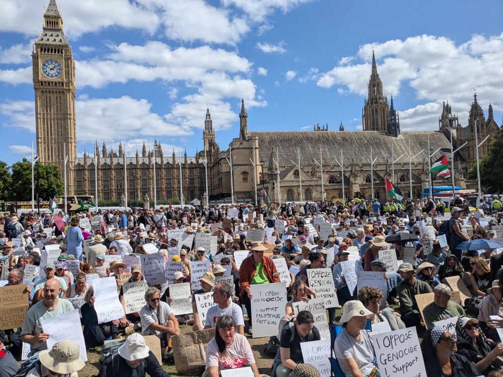 Thousands seen sitting with placards that all read “I oppose genocide. I support Palestine action.” Big Ben is seen in the background 