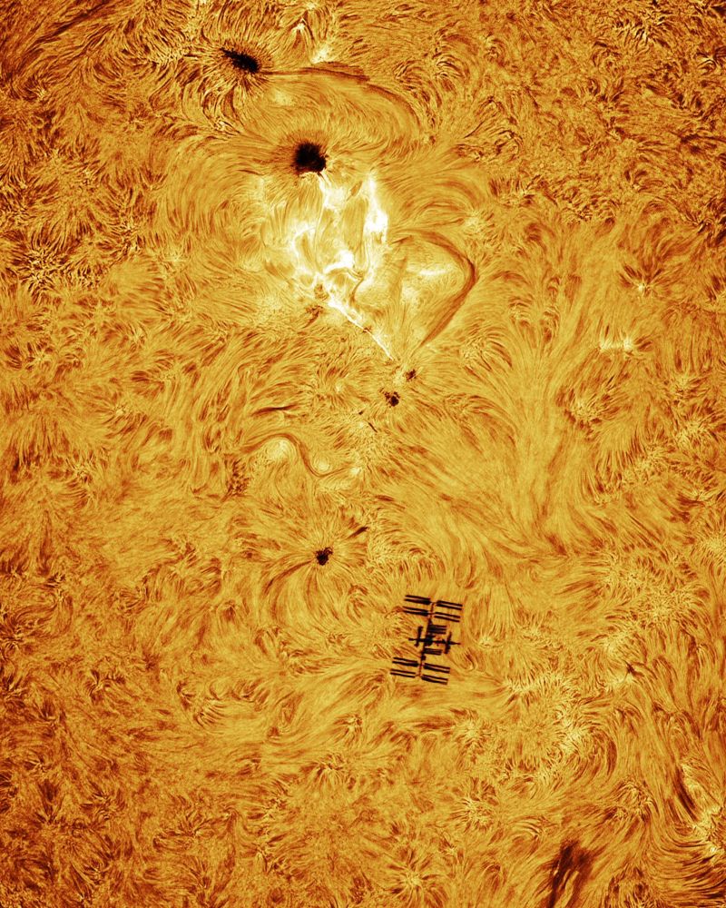 The frame is dominated by the burning sun, a mass of swirling inferno. In the bottom half of the picture, the silhouette of the ISS is clearly visible. Photo credit to Andrew McCarthy.