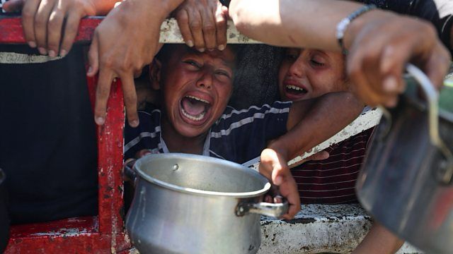 Starving Palestinians wait to receive food from a charity kitchen in Gaza City as Israel systematic policy of genocide and starvation continues. One boy in the centre of the photo is screaming in pain as he holds an empty pot for food.
Photograph credit to Mahmoud Issa of Reuters