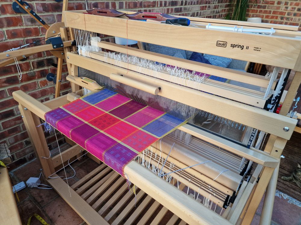 A louet spring 2 loom with pink and purple warp in stripes.