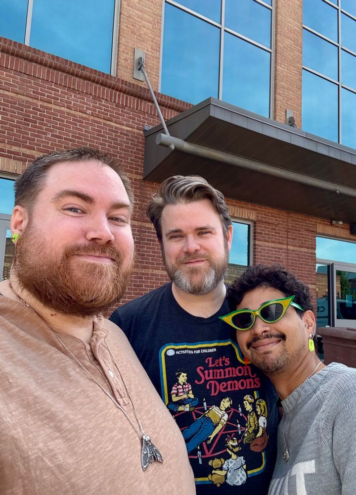 Picture of 3 people, all with beards looking at the camera and smiling 