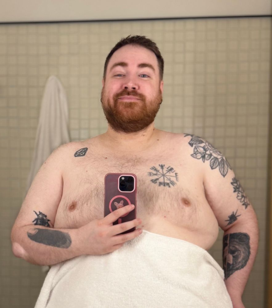 Mirror selfie showing off my bearded face and tattoos, with a towel covering my stomach 