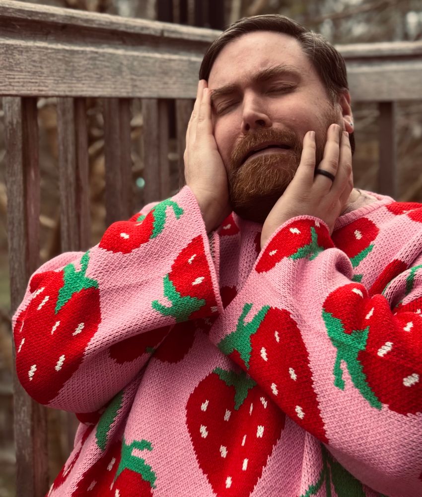 A photo of me sitting and making a face of exaggerated sadness, clutching my face with both hands. 