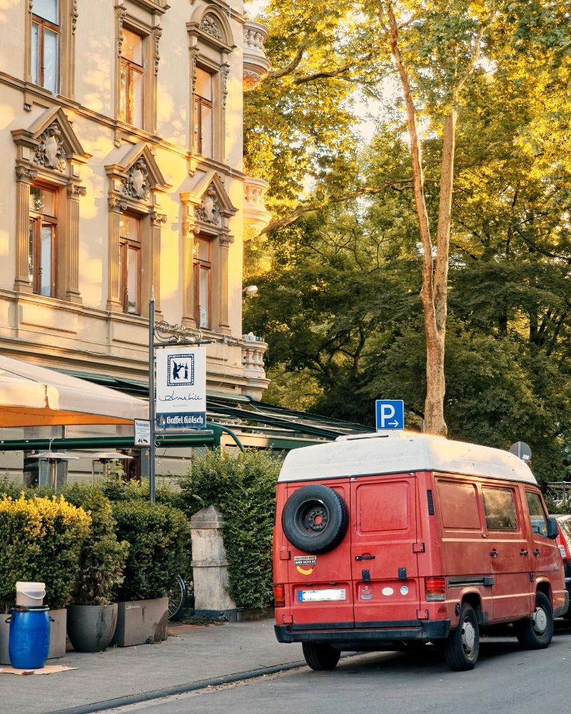 Red Merc MB100D RV sitting in a side street in beautiful morning light rendering the scene in somewhat lovely popping color sheme. 