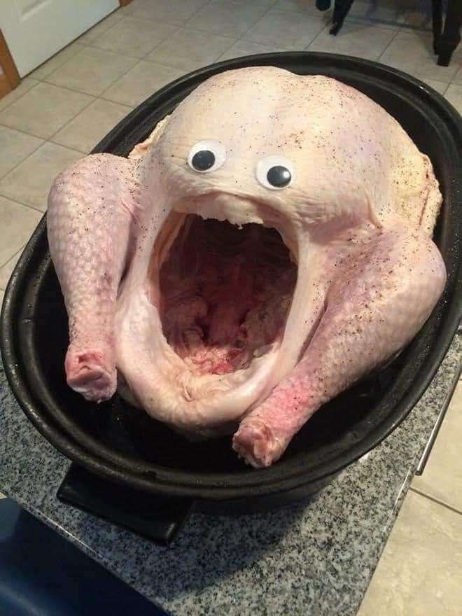 An uncooked turkey with googly eyes above the cavity giving it the appearance of screaming