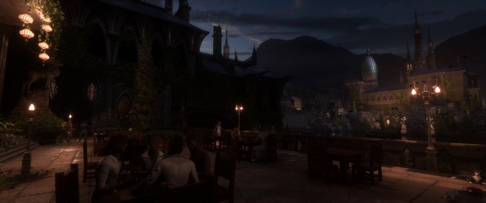 This image depicts a serene, atmospheric evening scene in a richly detailed fantasy city, blending gothic architecture with warm, lived-in charm.

The foreground shows an outdoor terrace café or tavern set along a stone promenade overlooking a quiet waterway. Several groups of people sit at wooden tables beneath the soft glow of lamplight, engaged in conversation or enjoying food and drink. Their clothing is varied—leather coats, tunics, and layered fabrics—suggesting a cosmopolitan and diverse population. A cat lounges comfortably near one of the far tables, adding to the sense of peaceful everyday life.

To the left, a large gothic building rises, draped in thick ivy and shadow. Arched windows with ornate tracery and decorative circular stained-glass features punctuate the dark stone façade. A carved stag statue stands on a pedestal near the entrance stairs, illuminated by a cluster of warm hanging lanterns that cast amber light across the foliage.

Across the water, the architectural skyline unfurls into a stunning vista: a complex of majestic buildings with domes, towers, and spires, all softly lit against the deep blue of twilight. The most striking feature is a large, egg-shaped glass dome that glows with a subtle turquoise sheen. Ivy climbs the structures on that side as well, lending the impression of an ancient city where nature and civilization have grown together over time.

Mountains rise in the distance, their dark silhouettes framed beneath a cloud-dusted night sky. A few stars are visible, and faint birds or bats can be seen circling near the far buildings.

Overall, the scene conveys a mood of quiet urban magic—a city at rest, full of history and life, where evening light mingles with gothic grandeur and warm communal spaces.
