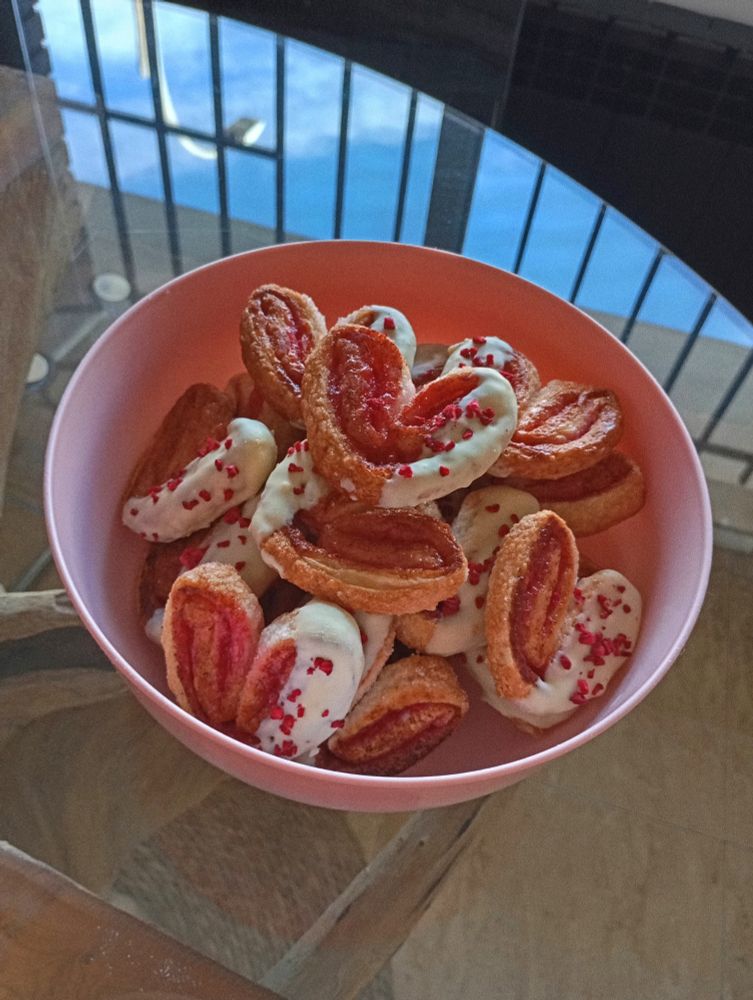 bol rosa lleno de palmeritas de hojaldre con chocolate blanco y pedacitos de frambuesa.