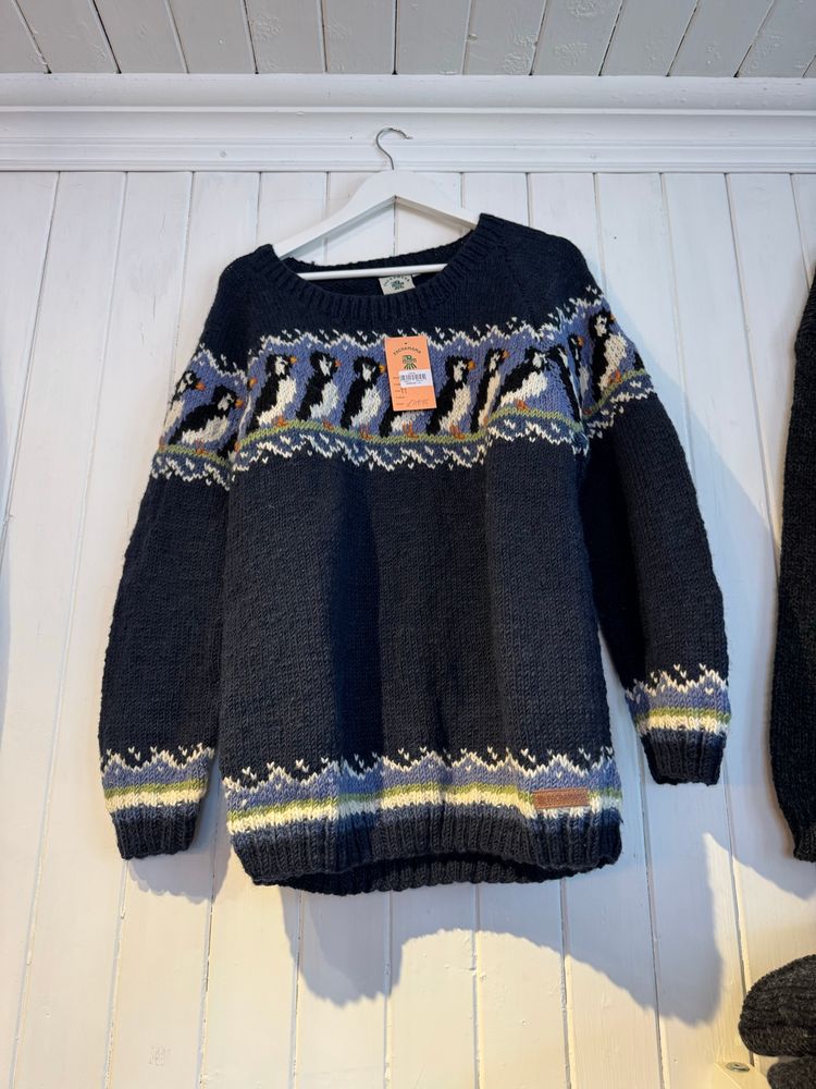 A jumper on a clothes hanger in a shop. It has a pattern around the top of puffins. Yes, PUFFINS! 
