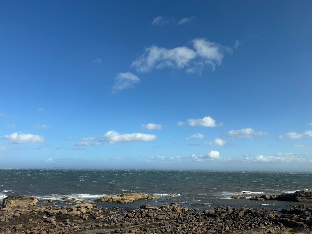 A photo of the Firth of Forth. Blue skies and rocky coast. 