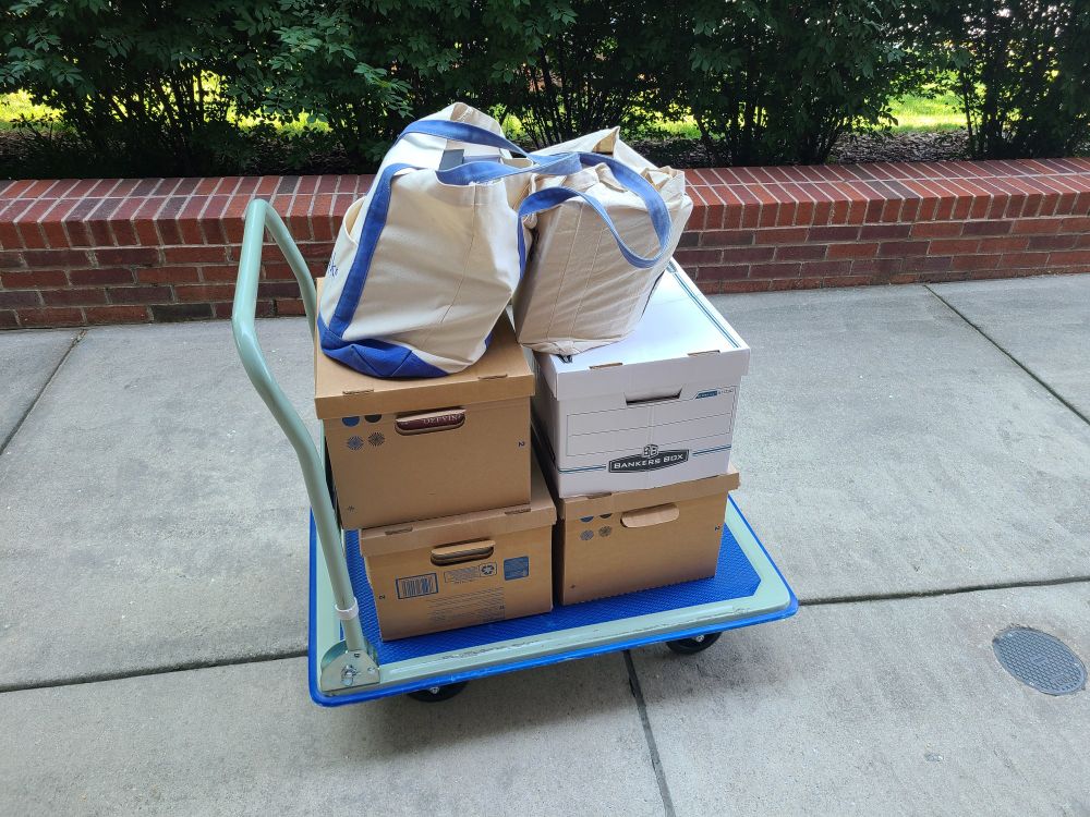 Rolling cart with 4 banker boxes and 2 large tote bags full of books