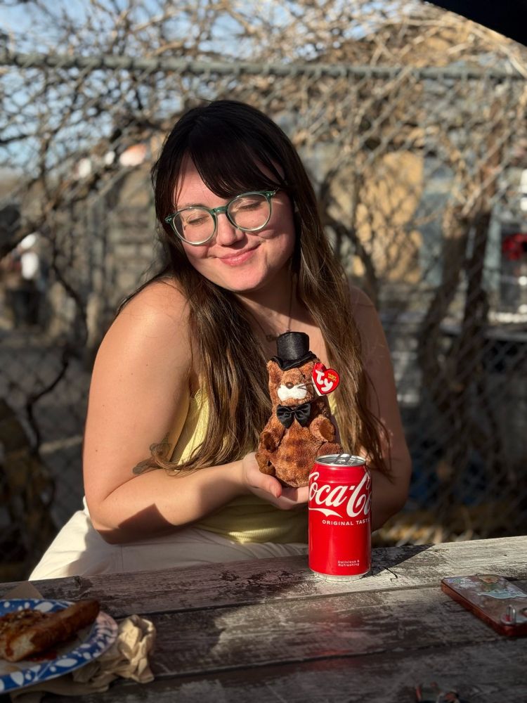 Clare holding Phil at a table outside, sponsored by Coca-Cola 