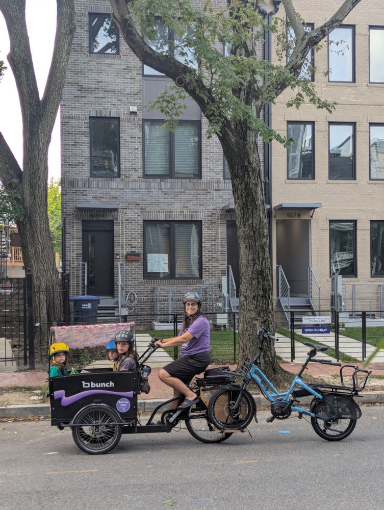 DC trike mom in a purple t-shirt on a bunch bike with three kids, towing a tern hsd. You can't see the cat litter but it's there 