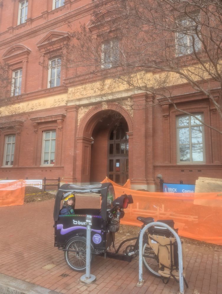 Bunch bike with two toddlers inside parked in front of the national building museum in downtown DC
