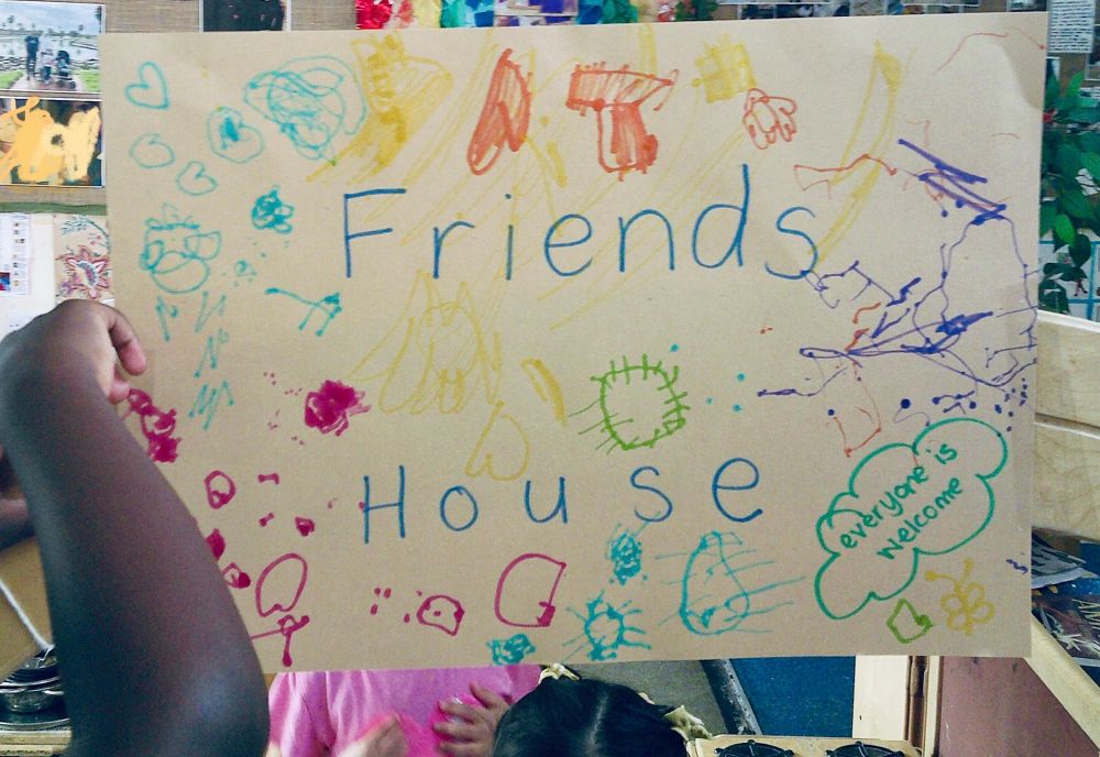 A child putting the poster up in the archway entrance to the home corner. 