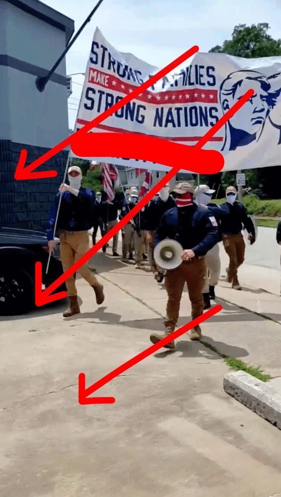 patriot front dorks with faces covered and matching outfits marching in formation.
