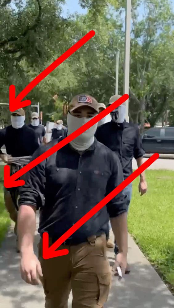 patriot front dorks with faces covered and matching outfits marching in formation.