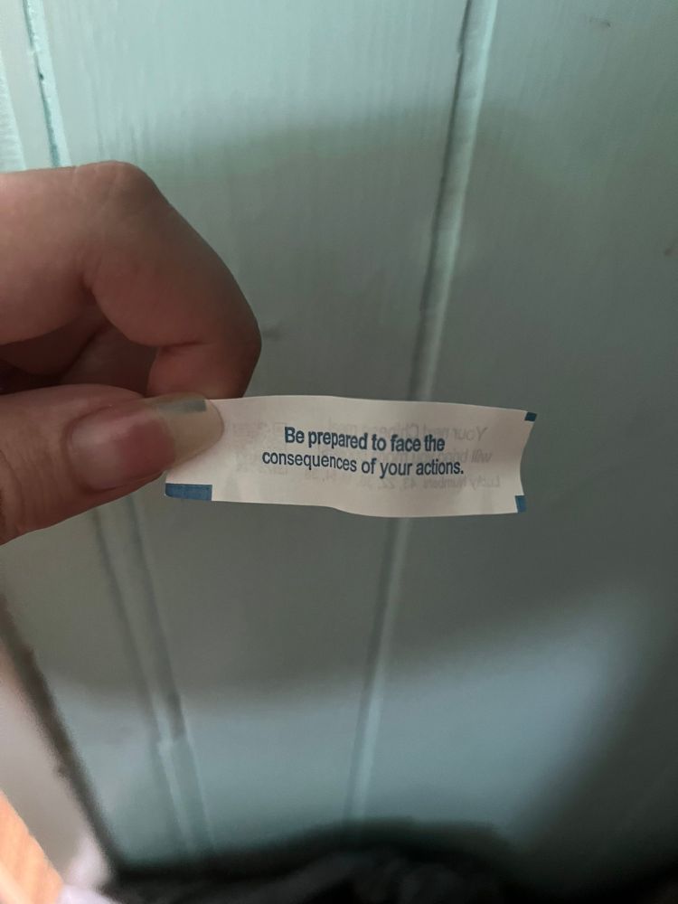 Picture of a hand holding a slip of fortune paper that reads "Be prepared to face the consequences of your actions."