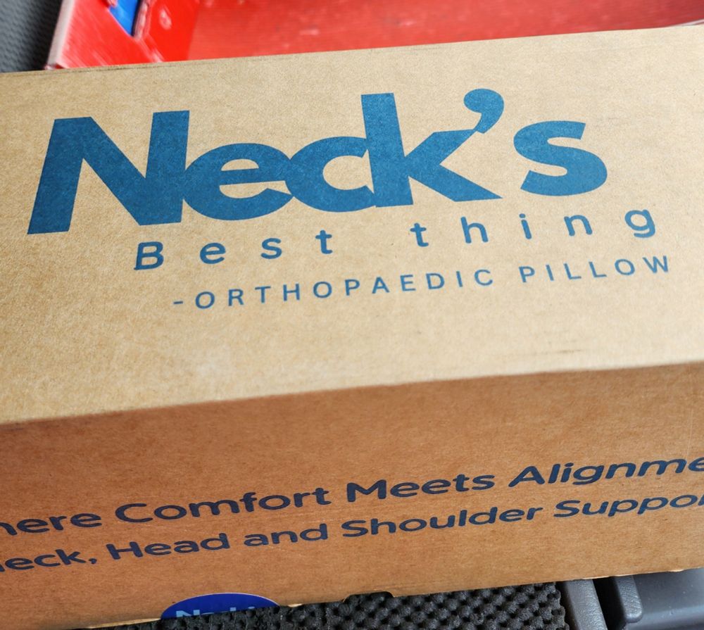 A boxed pillow that has in blue "Neck's best thing" orthopedic pillow 