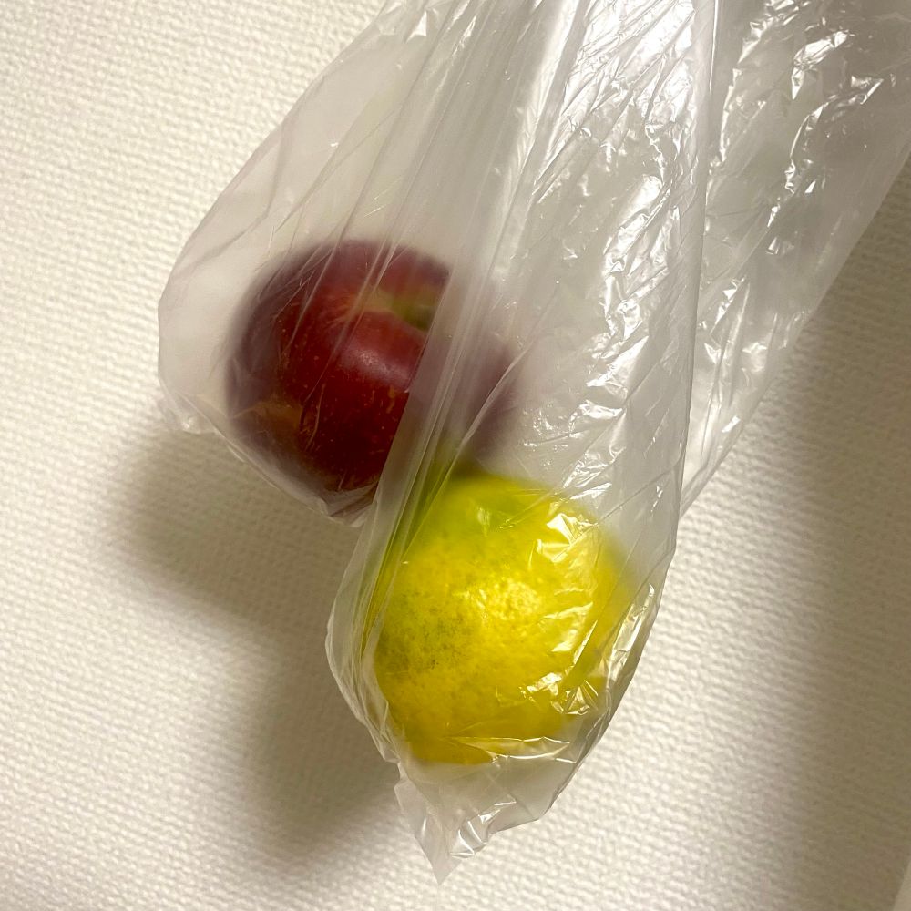 ビニール袋に入った林檎と柚子の写真