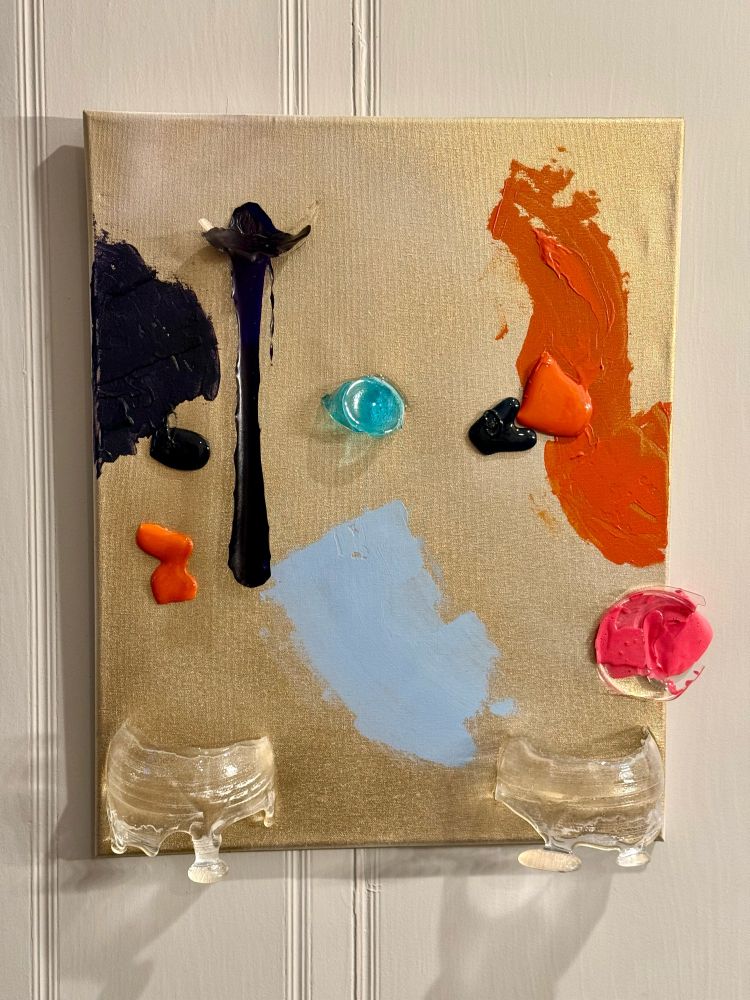 "The Divide Between Us" - A mixed media artwork on a metallic gold canvas. The composition features several key elements:

Two transparent glass domes anchor the bottom of the canvas, appearing as half-spheres that seem to emerge from the surface. Above each dome, contrasting painted areas spread across the canvas - a deep navy blue mass on the left and a vibrant orange expanse on the right. Each colored section has a small black glass accent piece embedded within it.

In the center, a striking turquoise blue glass element hovers between the opposing colors. Below it, a pale powder blue painted area creates a central focus. A small orange sculptural element sits near the left dome, while a bold pink paint and glass construction occupies the lower right corner.

Most distinctively, a thin black vertical paint form extends upward from the left side, ending in a wing-like flourish, with the paint appearing to be suspended away from the canvas surface. The entire piece measures 18x24 inches and combines painted elements with three-dimensional glass components to create multiple layers of depth.

The metallic gold background catches light differently across its surface, creating subtle variations in tone that interact with the more bold, opaque painted elements and transparent glass features.