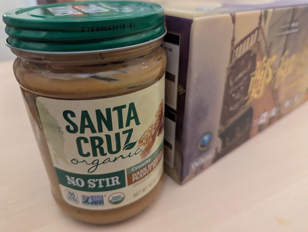 Close up of the side of the box for the new board game The Treasure Ship of Zheng He. Designer: Hisashi Hayashi. Artist: Yoshikazu Yasuhiko. Publisher: Harvest Valley. 

Next to the box is a jar of Santa Cruz organic peanut butter, for scale. The board game box is tall and CHONKY. 