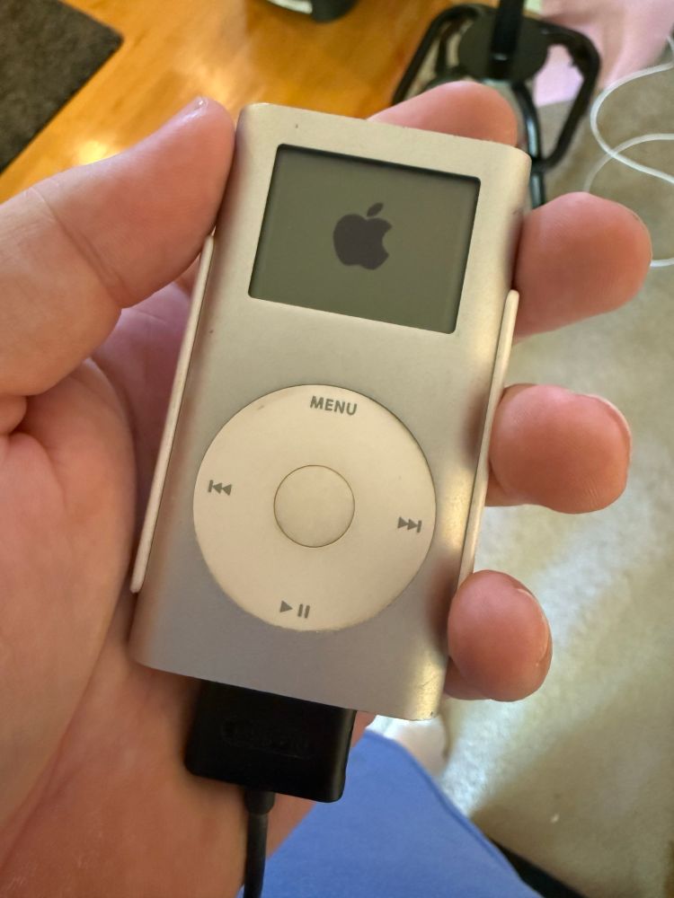 An Apple iPod Mini held in a hand with the boot logo showing