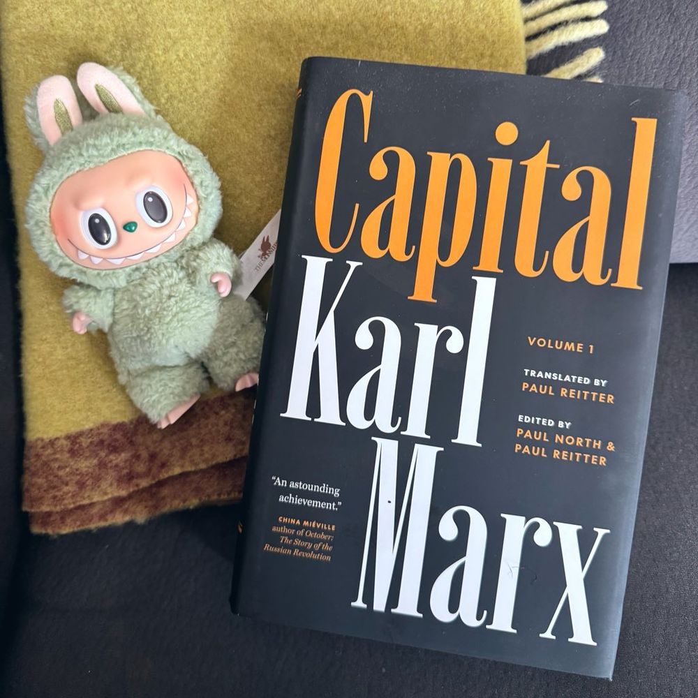 picture of a mint green labubu next to a copy of volume one of marx’s capital 