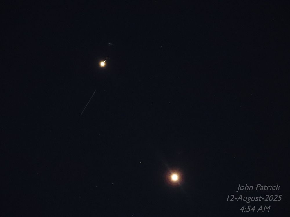 1 of 2
Photo: A black background with whitish dots of various sizes.  The largest dot, in the lower right is the planet Venus.  A slightly smaller dot in the upper left is the planet Jupiter. There are four tiny dots very close on either side of Jupiter (three above, one below) forming a diagonal line from bottom left to upper right.  They are Jupiter's Galilean moons - (from bottom to top: Callisto, Europa, Io, and Ganymede.  Below and to the left of Jupiter is a long diagonal line created by a passing satellite.  There are other tiny dots scattered through the photo, they are stars.

