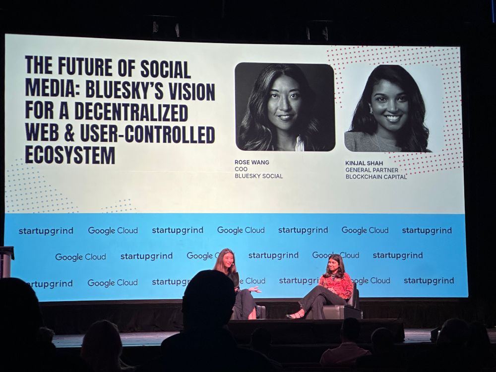 Photo of two women, Rose Wang and Kinjal Shah onstage at the 2025 StartupGrind conference. They’re seated in front of a large screen with the name of their talk, “The Future of Social Media: Bluesky’s Vision for a Decentralized Web & User-Controlled Ecosystem”.