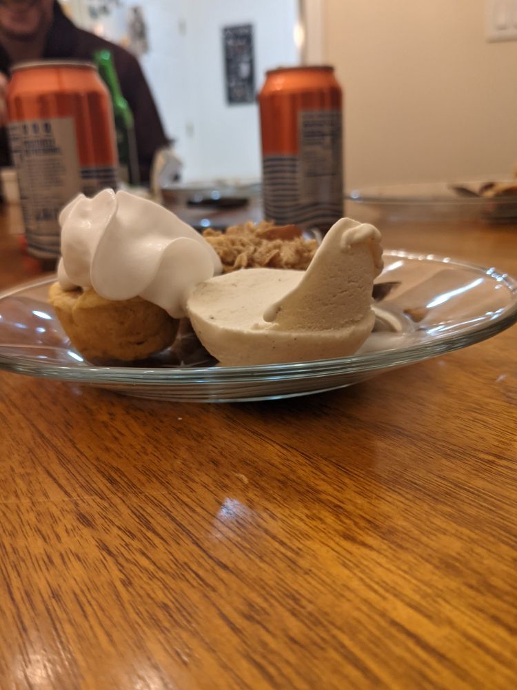 A dessert plate with a mini pumpkin pie and a mini apple pie and a scoop of ice cream