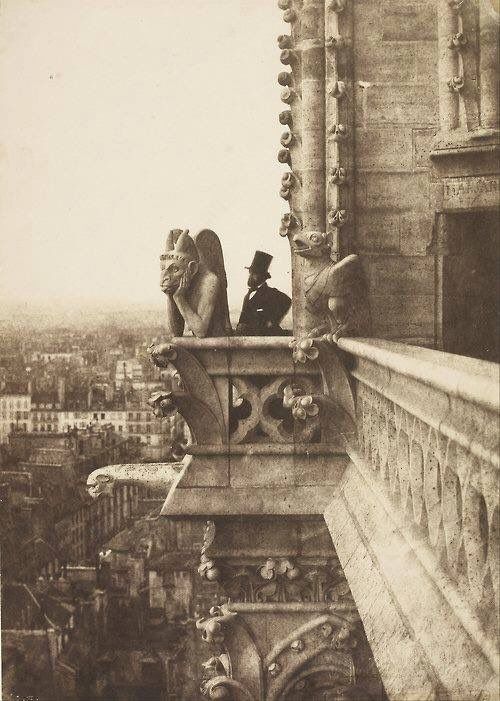 Man stands behind sad looking gargoyle 