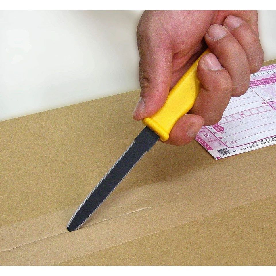 A yellow-handled "Canary" box-cutting tool, held in a person's hand, cutting paper tape on a cardboard box.