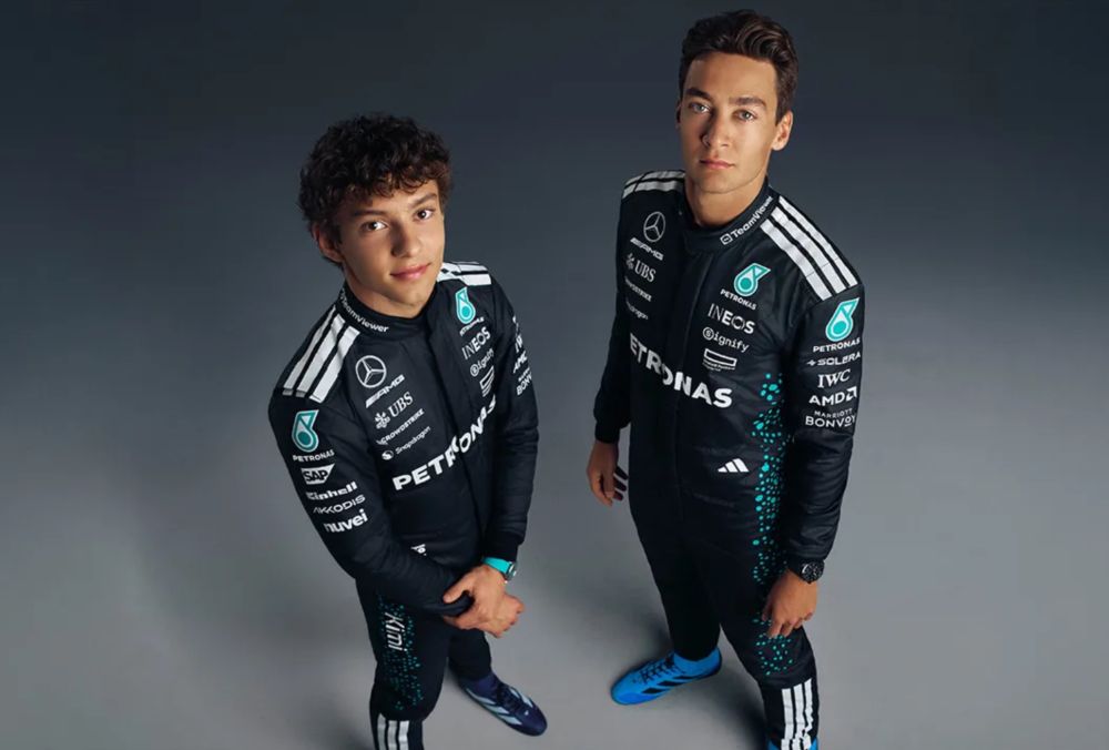 A professional photoshoot of Mercedes Formula One drivers Kimi Antonelli and George Russell. They are wearing Mercedes racing suits and looking up at the camera.