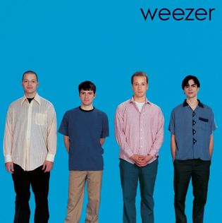 The picture shows the cover of the band Weezer’s first self-titled album with the 4 members of the band standing facing the camera in front of a plain blue background. It is known as “the blue album”