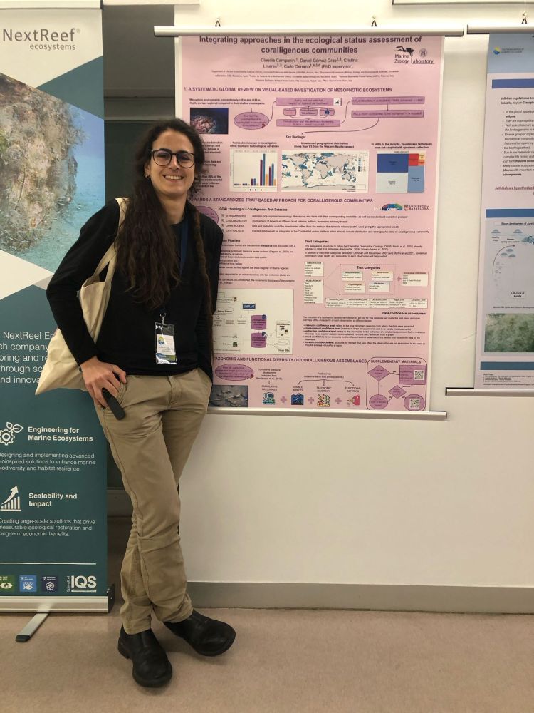 Claudia posing in front of the poster outlining their PhD project.